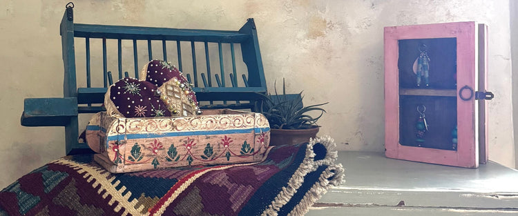 Painted wooden plate rack, hand-painted box with embroidered hearts and a pink key cupboard on a kilim